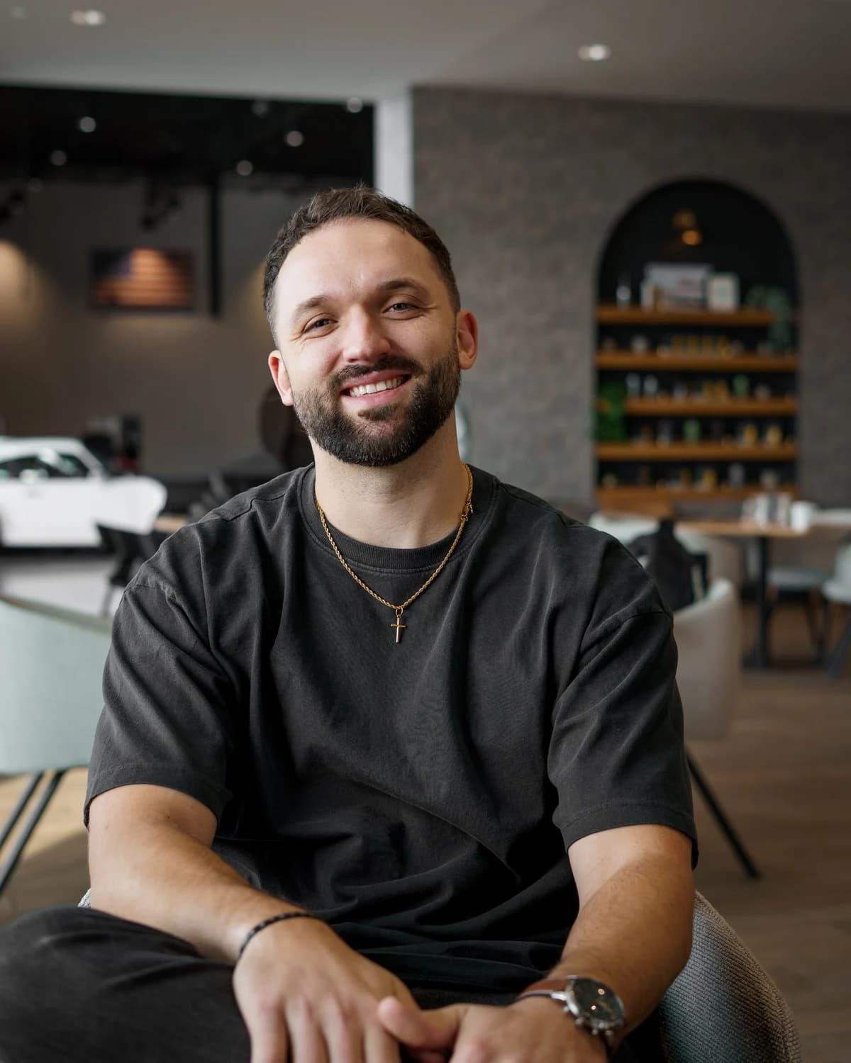 Kyle Hoffman smiling, seated in a bright cafe in a black T-shirt